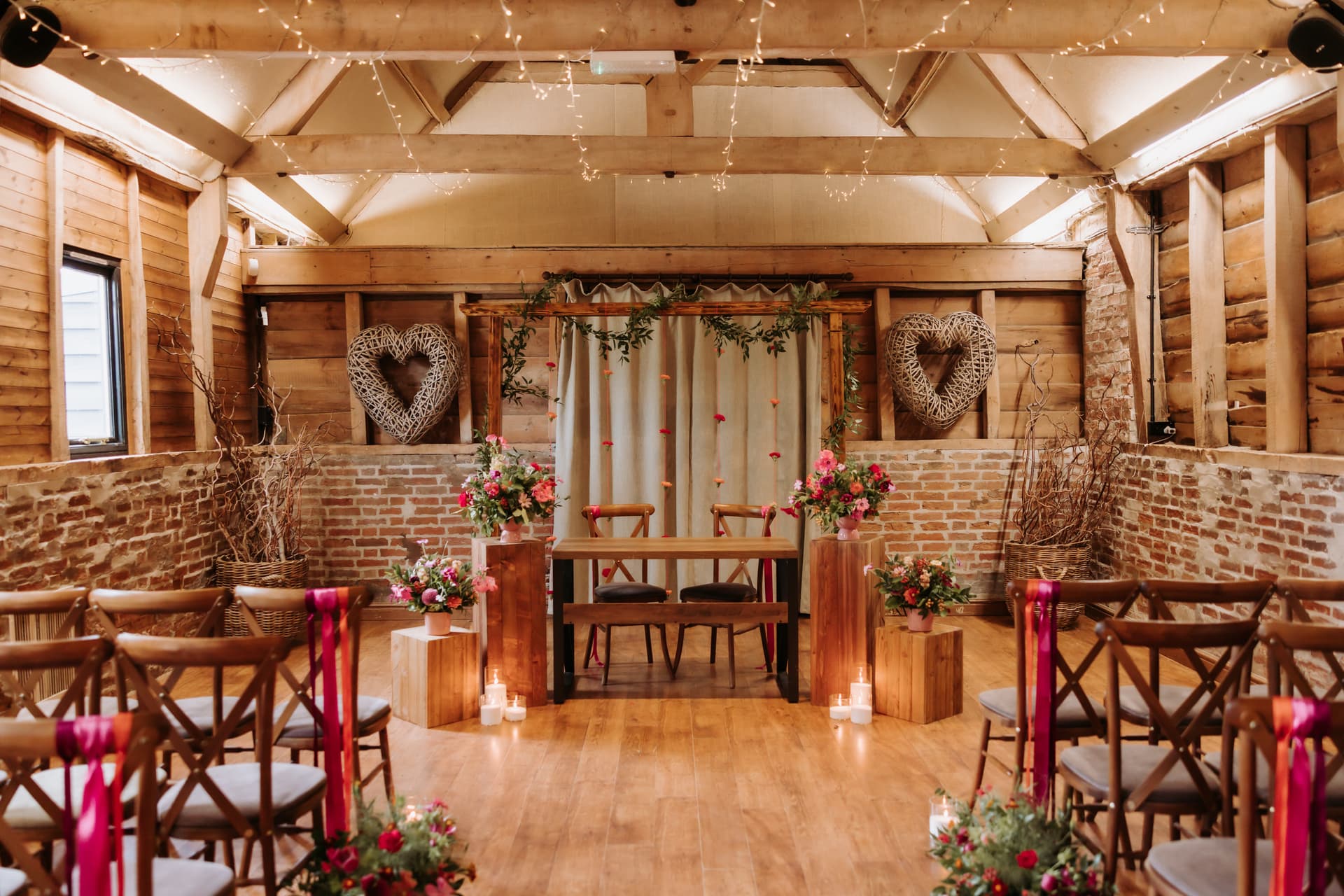 A groom celebrating at the top of the aisle, flowers up the barn wall behind