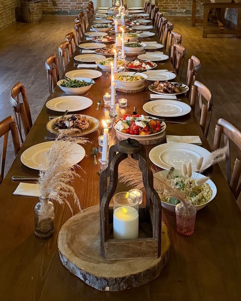 A long candlelit table set for supper inside the barn at Wellie Nest