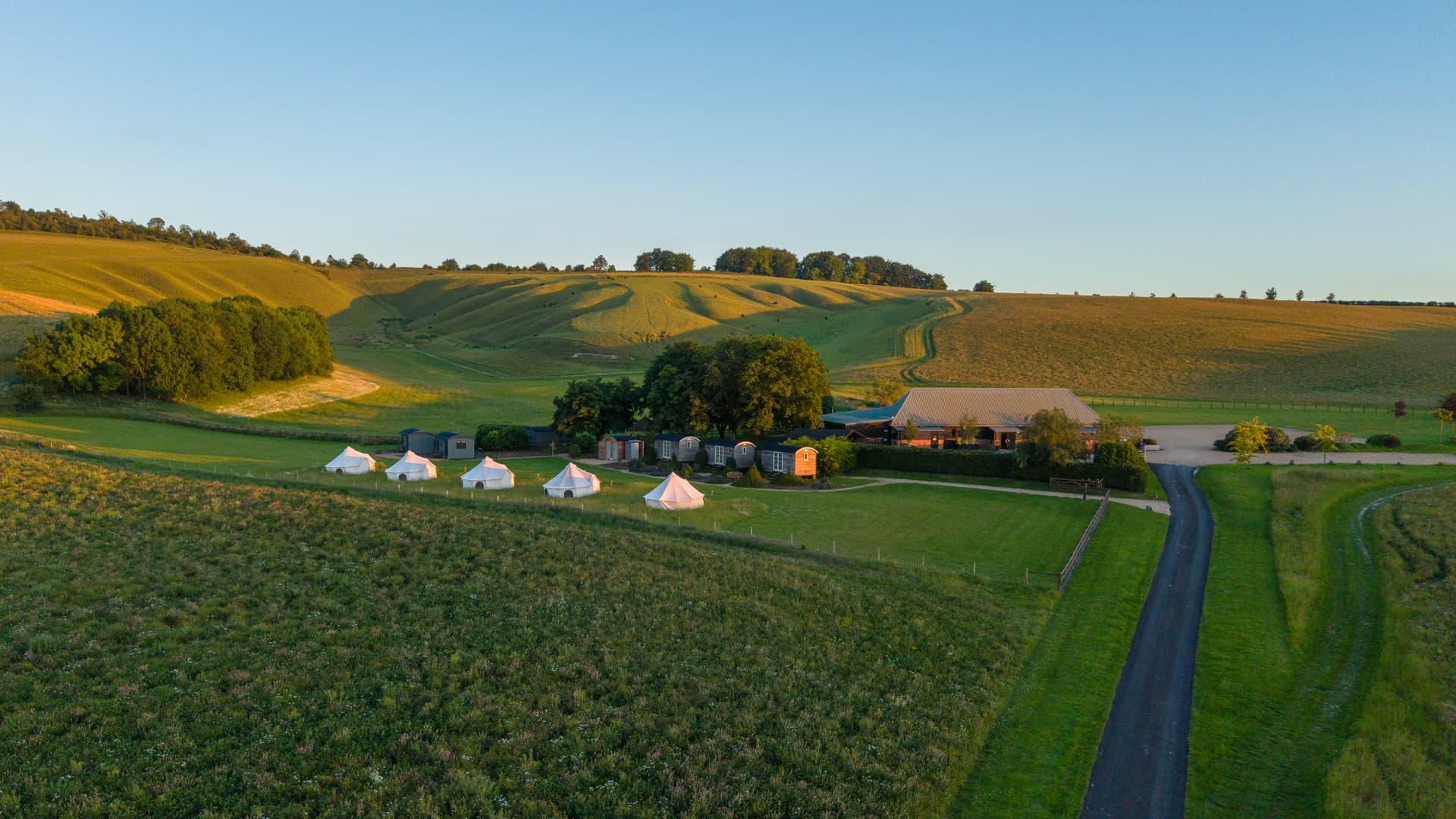 Aerial view over Wellie Nest, the tents, the barn and the Wiltshire hills