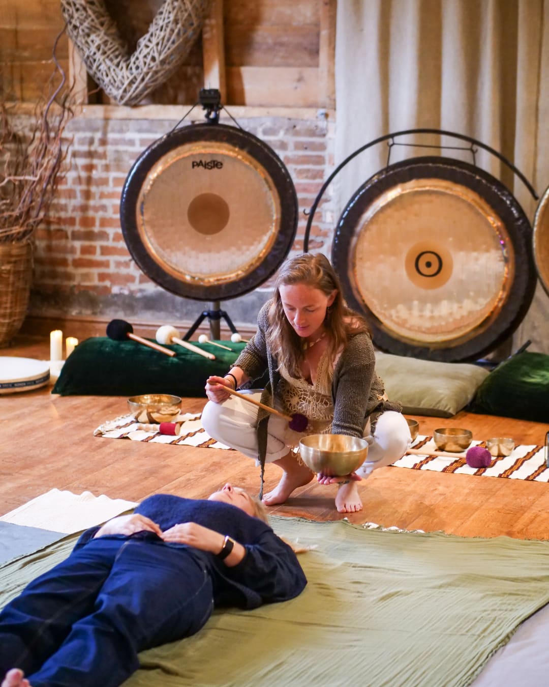 A practitioner leading a sound bath with gongs and singing bowls